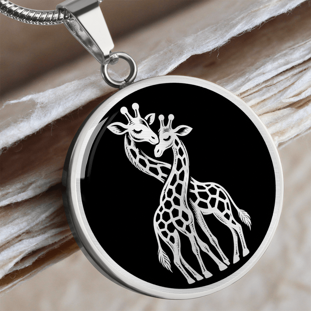 Silver-colored circular giraffe pendant with two affectionate giraffes crossing their necks in detailed white artwork on black.