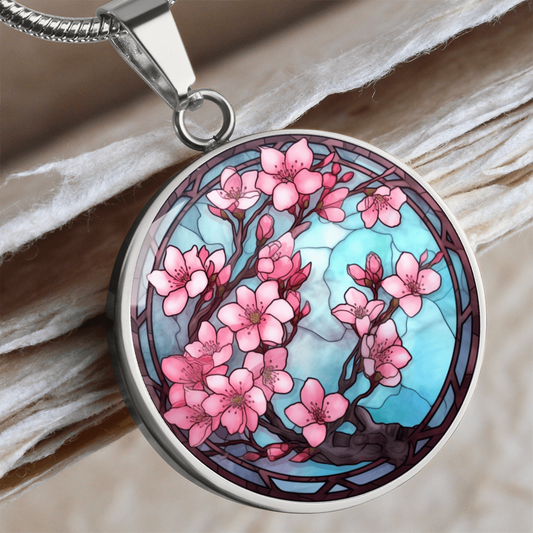 Cherry blossom necklace featuring pink sakura flowers on dark branches against a turquoise-blue stained-glass-style circular pendant.