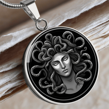 Silver-colored Medusa pendant featuring a detailed monochrome portrait with snake hair against black.