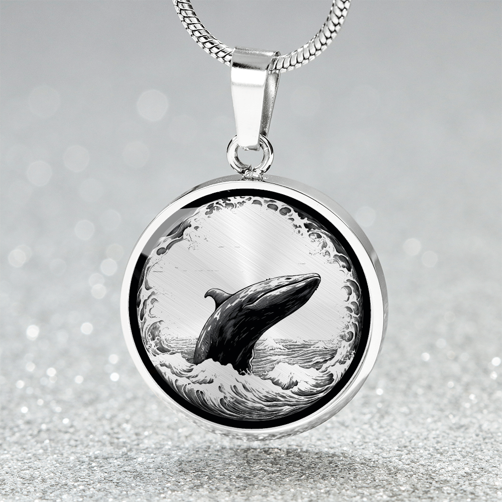 Breaching whale necklace with detailed black-and-white illustration of a whale rising from ocean waves on a silver-colored round pendant.