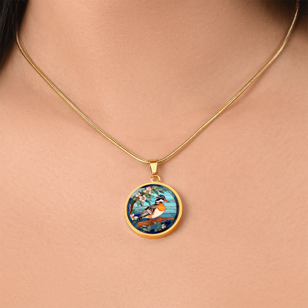 female wearing a gold Mandarin duck-inspired necklace featuring a colorful duck perched on a flowering branch against a turquoise-blue stained-glass-style background.