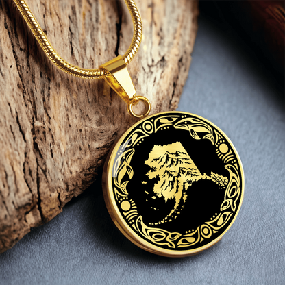 gold Alaska mountain pendant necklace featuring snowy peaks, black and white linocut artwork and an ornate circular border.