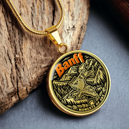 Gold finish Banff Canadian Rockies pendant with orange Banff lettering, pine forest, mountain peaks and Moments of Awe design