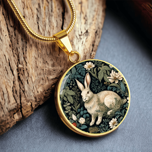 Botanical rabbit necklace featuring a cream-colored bunny surrounded by ivory daisies and sage-green foliage on a dark round pendant.