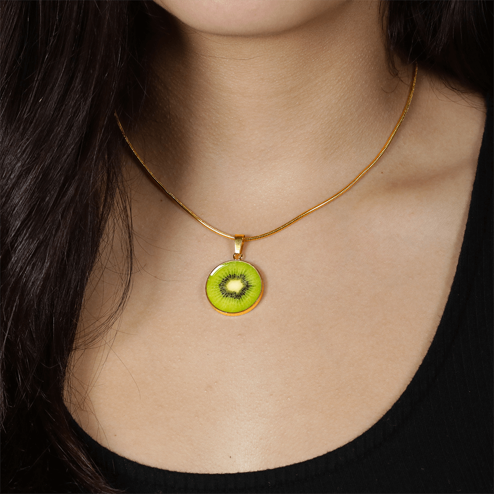 Woman wearing a Kiwi fruit necklace featuring a vivid green kiwi slice with black seeds and pale center on a round silver-colored pendant.