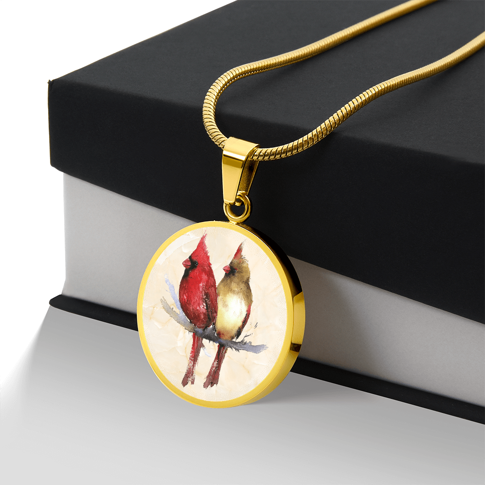Northern Cardinal pair necklace showing a bright red male and golden-brown female cardinal perched together on a branch against a light watercolor background. with gift box