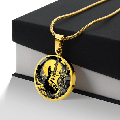 Electric guitar necklace featuring a black Strat-style guitar with cream pickguard against intricate black and gold artwork on a round pendant.
