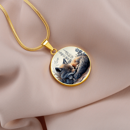 gold Sleeping fox necklace featuring a curled-up red fox with warm orange fur among soft blue-grey woodland foliage on a circular pendant.