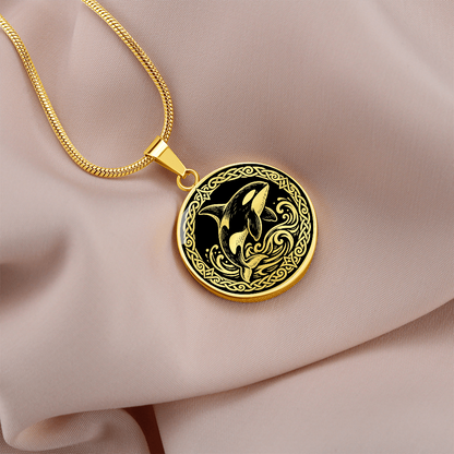 Gold orca whale necklace with decorative Viking-inspired border on pale fabric