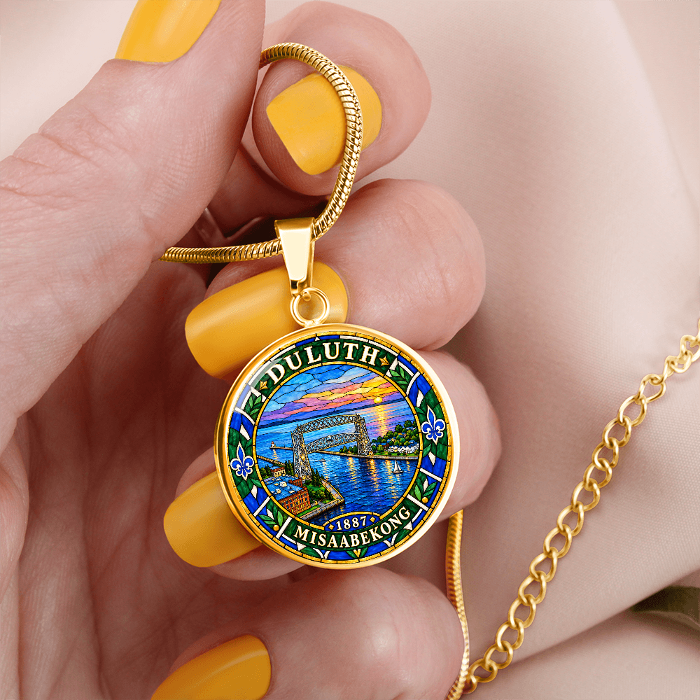 Gold finish Duluth harbor pendant necklace showing the Aerial Lift Bridge, blue lake water, sunset, fleur-de-lis motifs and Duluth lettering