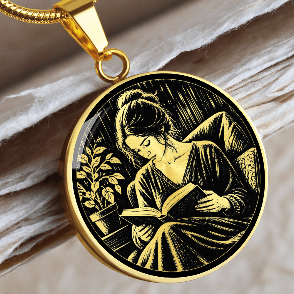 Silver-colored round book lover Gold necklace with black-and-white linocut-inspired illustration of a woman reading indoors.