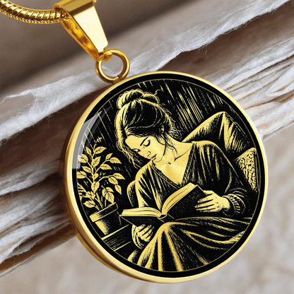 Silver-colored round book lover Gold necklace with black-and-white linocut-inspired illustration of a woman reading indoors.