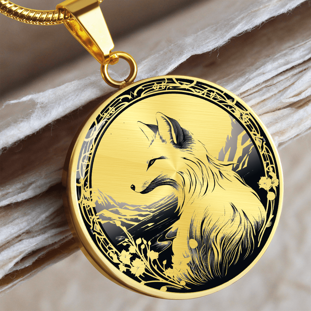 Gold Monochrome fox necklace featuring a seated fox with a bushy tail, distant mountains and decorative floral border on a round pendant.