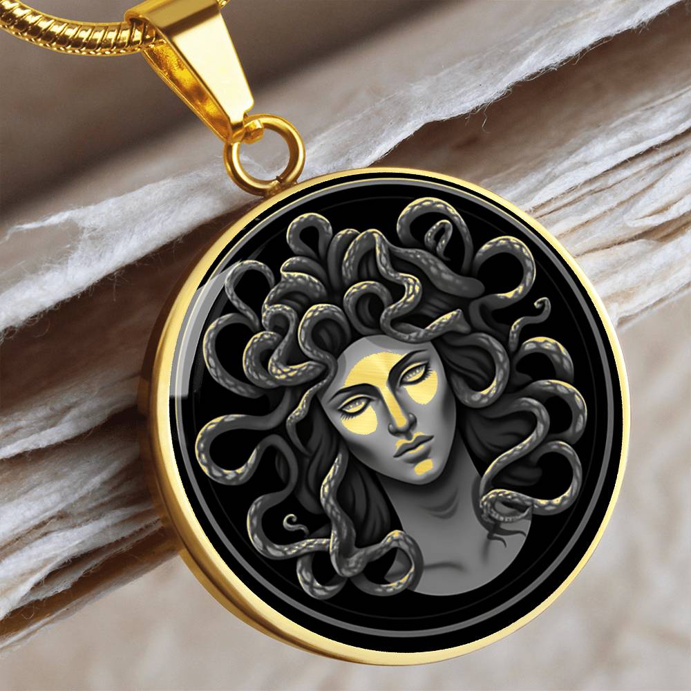 Gold finish circular Medusa necklace with silver-grey serpent-haired Gorgon portrait on a black background.