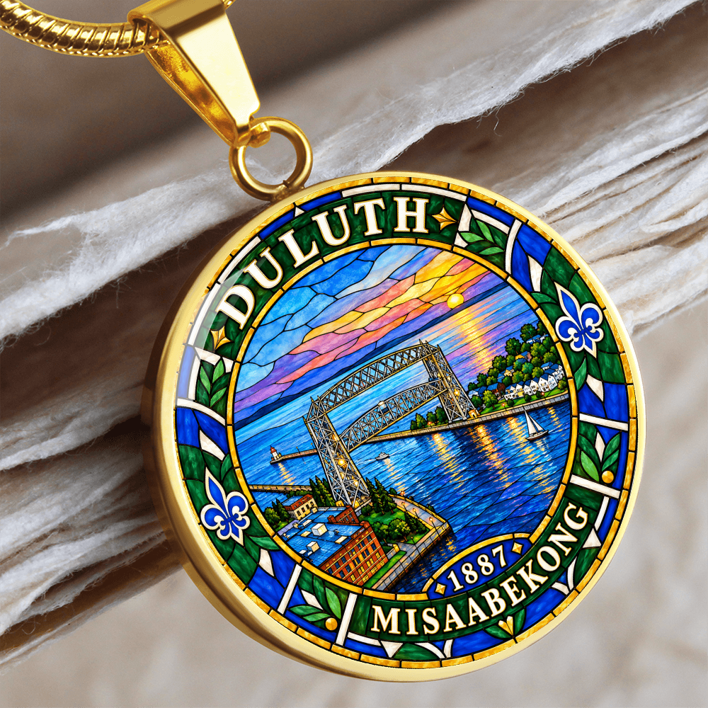 Gold finish Duluth harbor pendant necklace showing the Aerial Lift Bridge, blue lake water, sunset, fleur-de-lis motifs and Duluth lettering