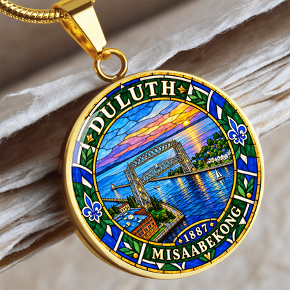 Gold finish Duluth harbor pendant necklace showing the Aerial Lift Bridge, blue lake water, sunset, fleur-de-lis motifs and Duluth lettering