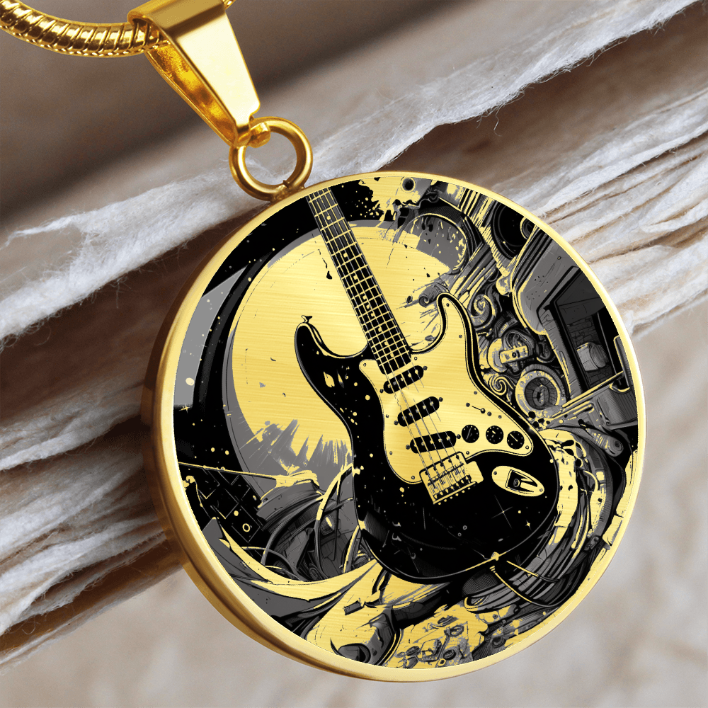 Electric guitar necklace featuring a black Strat-style guitar with cream pickguard against intricate black and gold artwork on a round pendant.