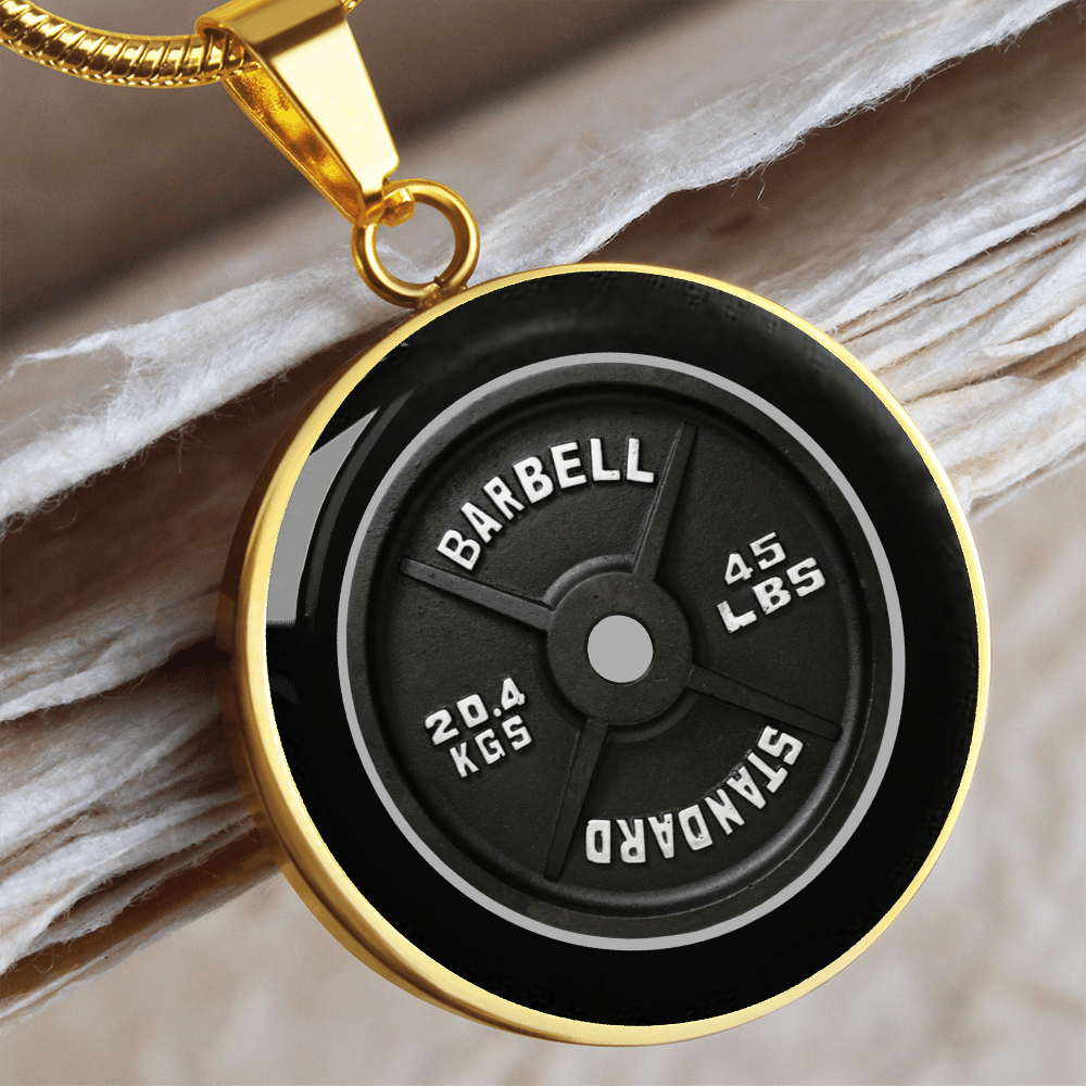 45 lb weight plate necklace with gold realistic black barbell plate artwork and 45 LBS 20.4 KGS markings on a round pendant.