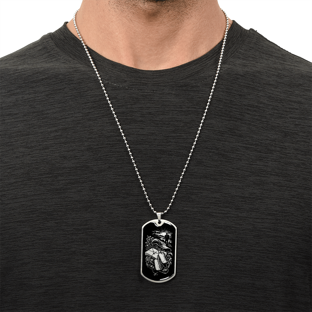 Polished silver military deployment dog tag with white-on-black illustration of letters, backpack, dog tags and distant walking figure.