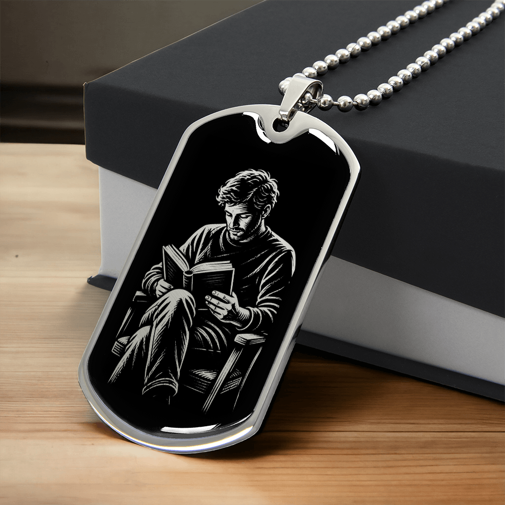 Silver-colored dog tag necklace showing black-and-white artwork of a man reading a book in an armchair.