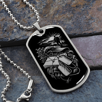 Polished silver military deployment dog tag with white-on-black illustration of letters, backpack, dog tags and distant walking figure.