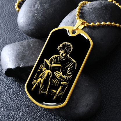Man reading dog tag necklace featuring linocut-style artwork of a seated man holding an open book against a black background.