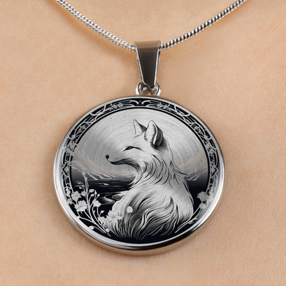 A round silver pendant necklace featuring a detailed black and white illustration of a fox, displayed on a person's skin with a silver chain visible at the top.