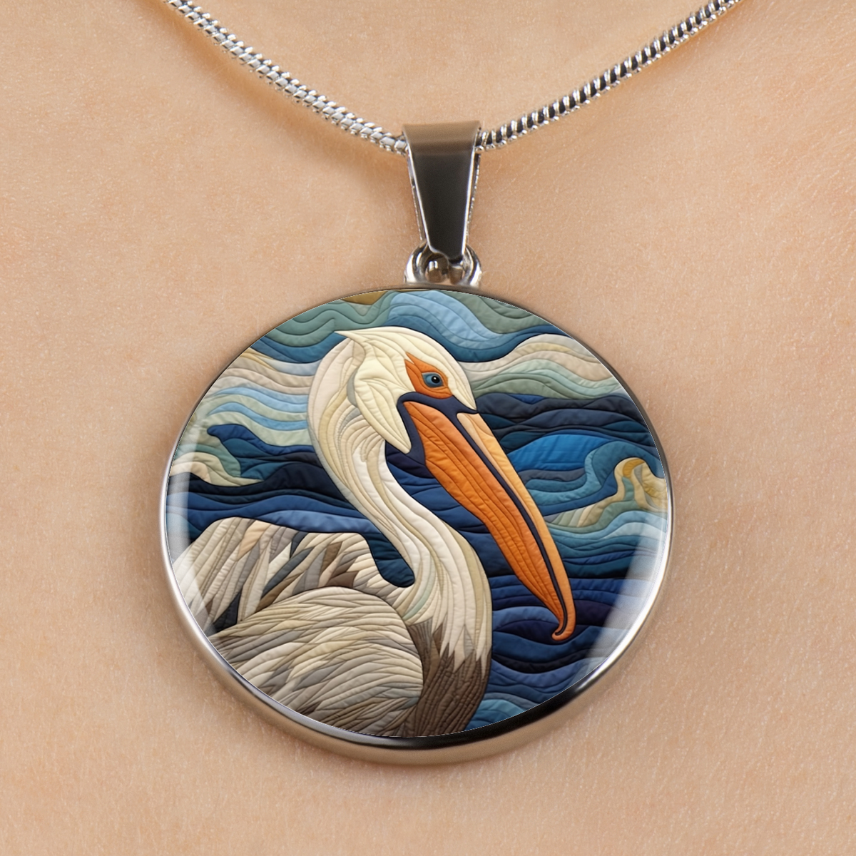 A round pendant necklace featuring a stylized pelican illustration with blue waves, shown worn on a person's neck against a light skin tone background.