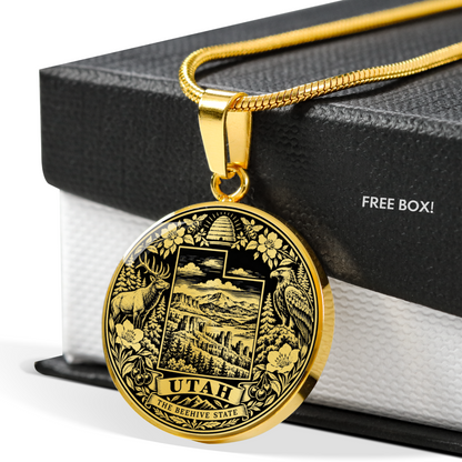A gold-toned Utah state seal pendant necklace displayed on a black gift box with the text 'FREE BOX!' visible on the side.